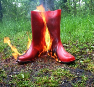 rote Gummistiefel in gelben Flammen vor grünem Hintergrund