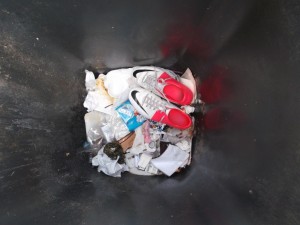 Die geilen weggeworfenen Fußballschuhe spiegeln sich in den Seiten der Mülltonnenwandung.