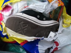 Die Chucks lagen ganz unten in der Mülltüte und hatten sich durch den oben liegenden Abfall schon ihrem bunten Gefängnis und ihrem Schicksal im Dreck ergeben.