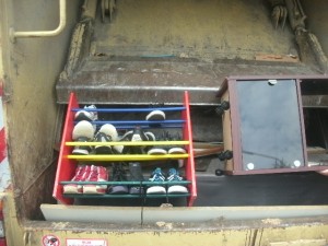 Der eine Müllfahrer bemerkte, dass das Schuhregal etwas zu weit außen stand und es bestand die Gefahr, dass es bei der Bewegung des Pressschildes auf die Straße kippen könnte. also schnell ein Schubser und es lag genau richtig um gepresst zu werden. Das war auch das Ende der schön anzusehenden Ordnung!