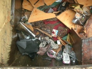 Das Pressschild öffnete sich zum &quot;Nachfassen&quot; und die ganzen Trümmer und Müllschuhe rutschten in die Müllschüttung; - aber nicht alle wie z. B. die zermalmte Stiefelette am oberen Bildrand.