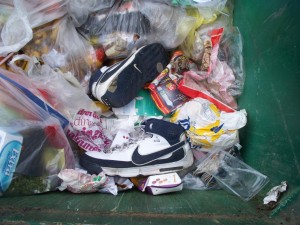 Große Turnschuhe in einem großen Müllcontainer; - das passt gut!