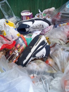 Von dort wo ich stand, um dieses Foto zu machen, wurden die Nikes in die Containermulde ganz durch nach hinten geschmissen, so dass die Turnstiefel wg. dem Schwung durch und über den Müll kullerten.